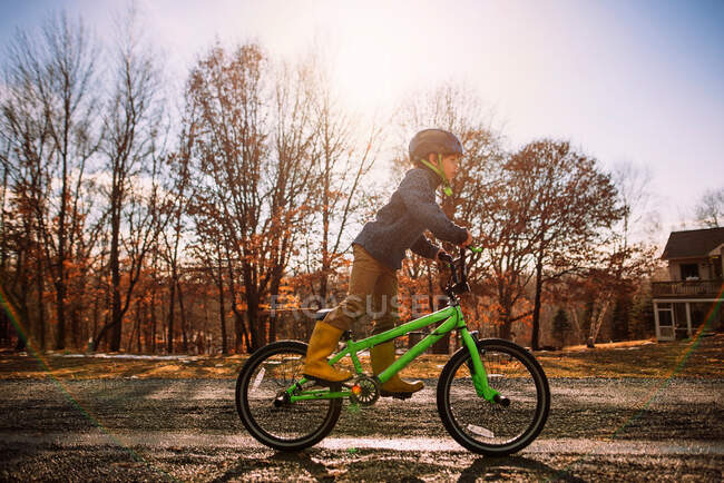 Мальчик на велосипеде по мокрой дороге весной, США — стоковое фото