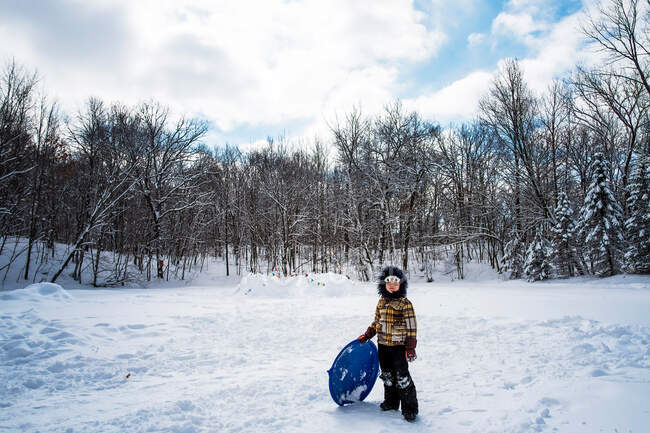 Мальчик, стоящий в снегу со своими санями, США — стоковое фото