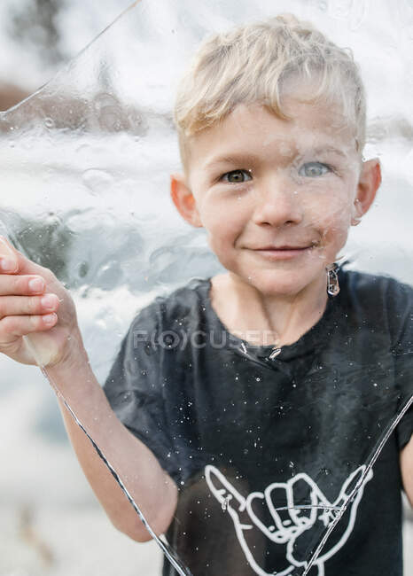 Porträt eines lächelnden Jungen, der durch eine Eisdecke blickt — Stockfoto