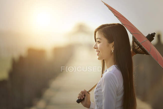 Porträt einer schönen Frau, die auf der Ubien-Brücke steht und einen Sonnenschirm hält, Mandalay, Myanmar — Stockfoto