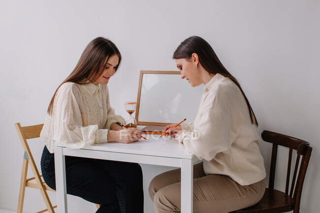 Dos mujeres sentadas en una mesa haciendo una lluvia de ideas - foto de stock