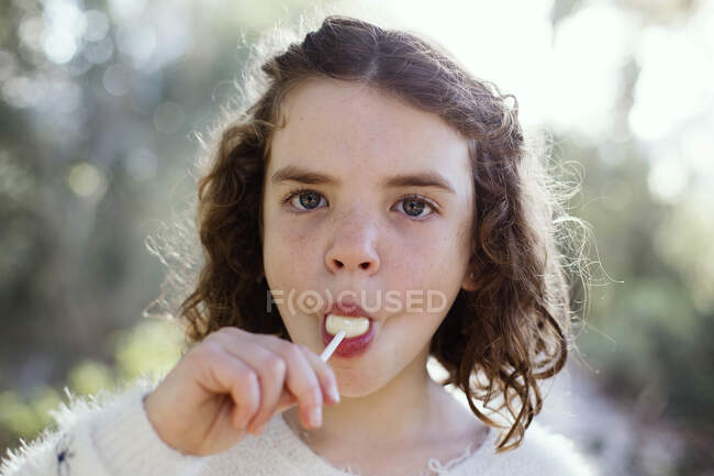 Retrato de uma menina comendo um pirulito na natureza — Fotografia de Stock