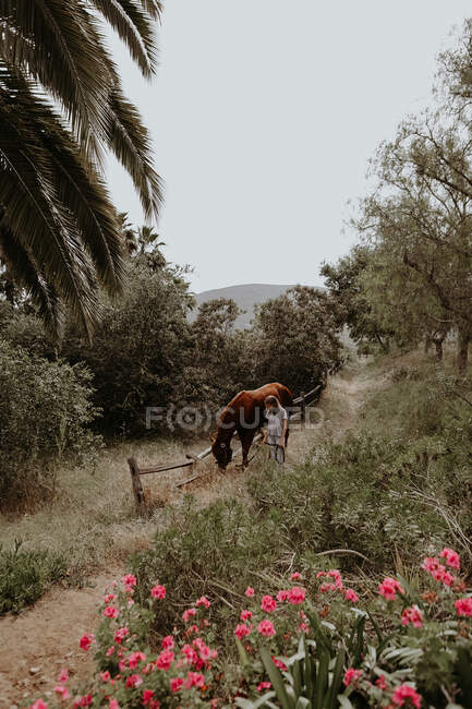 Menina caminhando através da paisagem rural com seu cavalo, Califórnia, EUA — Fotografia de Stock