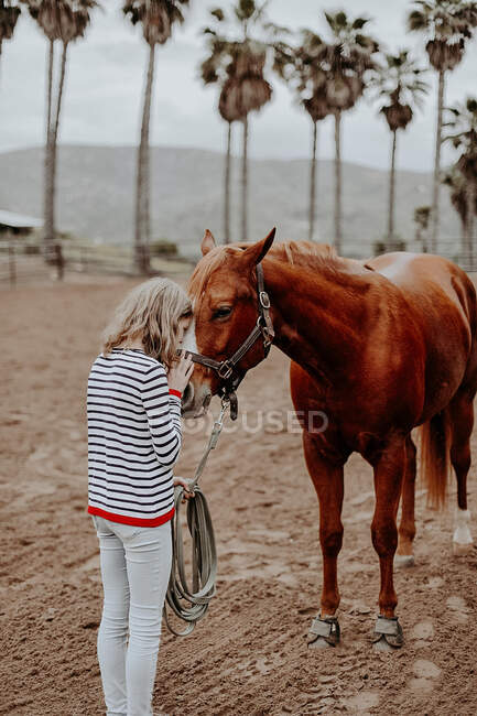Ragazza in piedi su un ranch baciare un cavallo, California, Stati Uniti d'America — Foto stock