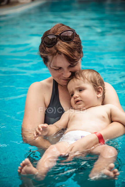 Mujer sonriente en una piscina marchita bebé hijo, Bulgaria - foto de stock