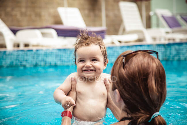 Vista trasera de una madre en una piscina con su hijo pequeño, Bulgaria - foto de stock