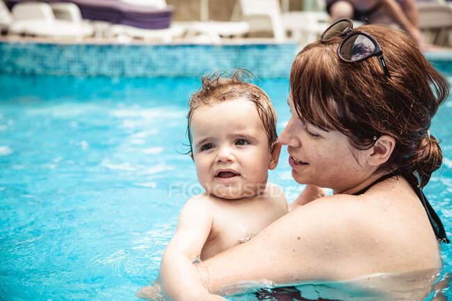 Bonne mère nageant dans une piscine avec son bébé fils, Bulgarie — Photo de stock