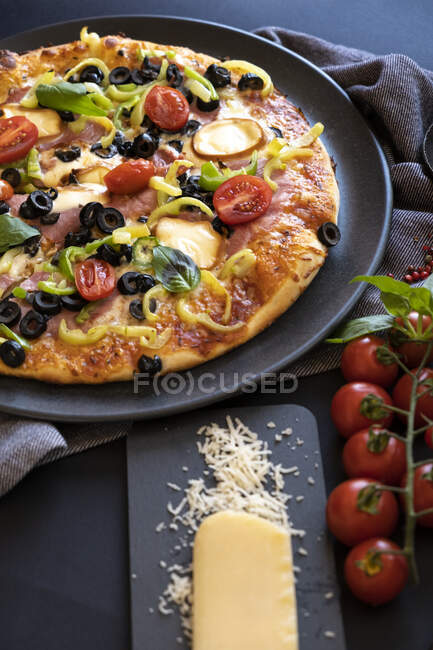 Крупный план ветчины, помидоров, оливок, перца и луковой пиццы — стоковое фото