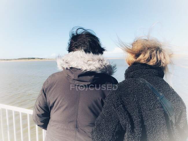 Due donne spazzate dal vento in piedi su una barca guardando la costa, Fanoe, Jutland, Danimarca — Foto stock