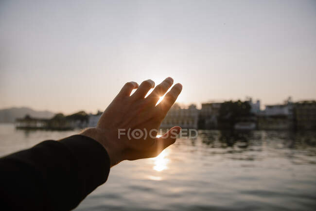 La mano del hombre alcanzando el sol, Udaipur, Rajastán, India - foto de stock