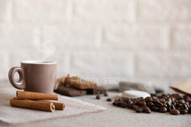 Tasse Kaffee, Proteinriegel, geröstete Kaffeebohnen und Zimtstangen — Stockfoto