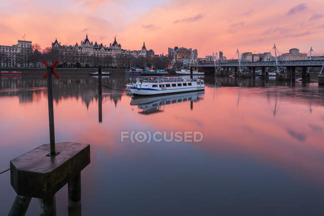 Barcos en el río Támesis por Whitehall y Hungerford Bridge al amanecer, Londres, Inglaterra, Reino Unido - foto de stock