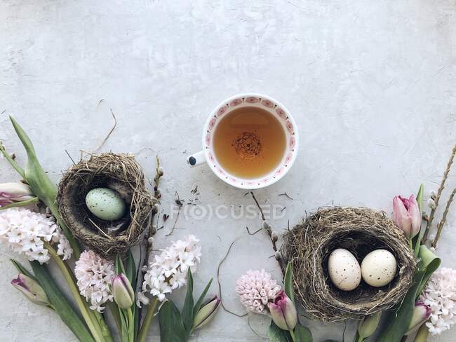 Uova di Pasqua in nidi con fiori e tè — Foto stock