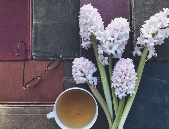 Libros antiguos, flores, gafas y una taza de té - foto de stock