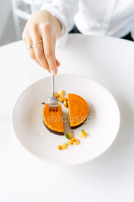 Close-up of a businesswoman eating sea buckthorn cheesecake while working — Stock Photo