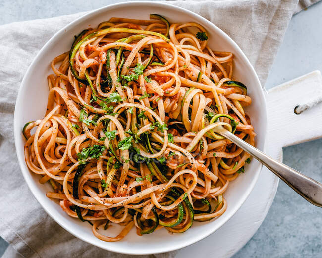 Espaguetis con calabacín, salsa de tomate y perejil fresco - foto de stock