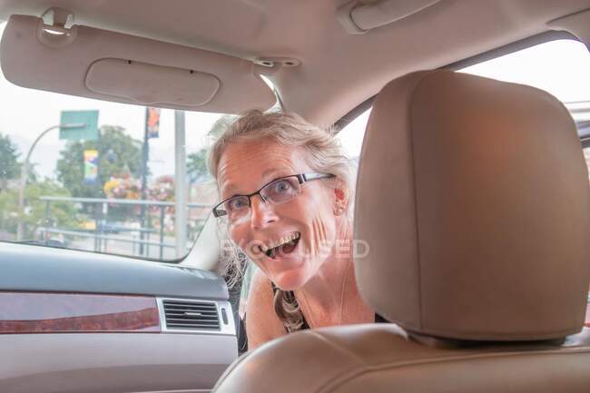 Femme souriante sautant dans une voiture — Photo de stock
