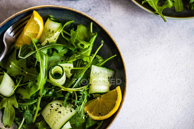 Healthy vegetable salad with aragula,  avocado and sesame seeds on concrete background with copy space — Stock Photo