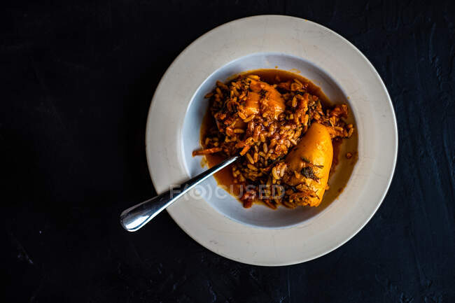Peperoni ripieni vegani con riso, carota e pomodoro con erbe di coriandolo serviti su fondo pietra con spazio per copiare — Foto stock
