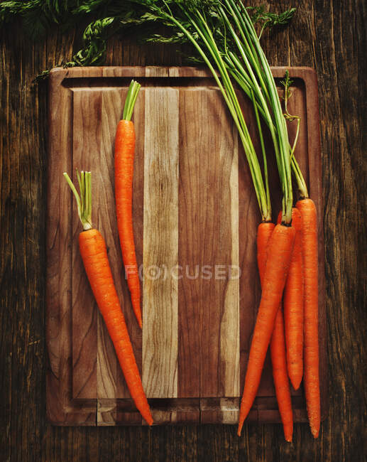 Zanahorias frescas en una tabla de cortar de madera - foto de stock