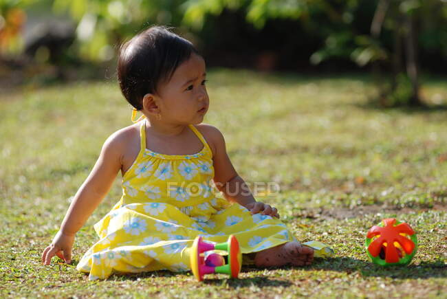 Девушка сидит в парке и играет с игрушками, Индонезия — стоковое фото