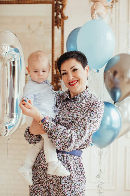 Portrait of a smiling woman holding her grandson on his 1st birthday — Stock Photo