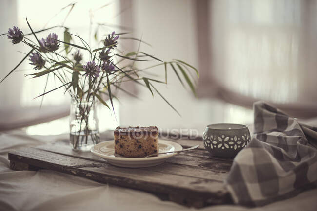 Kuchenstück auf einem Tablett mit Blumen und einer Kerze — Stockfoto