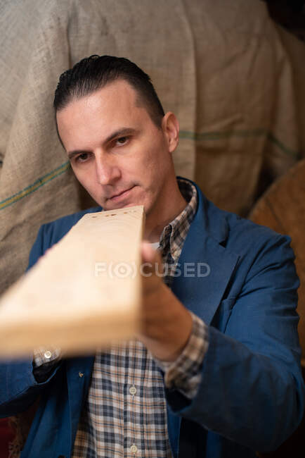 Carpinteiro olhando para uma tábua de madeira verificando seu trabalho — Fotografia de Stock