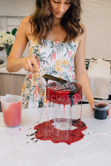 Donna smaltatura una torta di cioccolato di velluto rosso fatta in casa — Foto stock