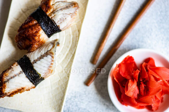 Rouleau de sushi avec des bâtonnets de saumon, baguettes, sur une assiette, nourriture japonaise — Photo de stock