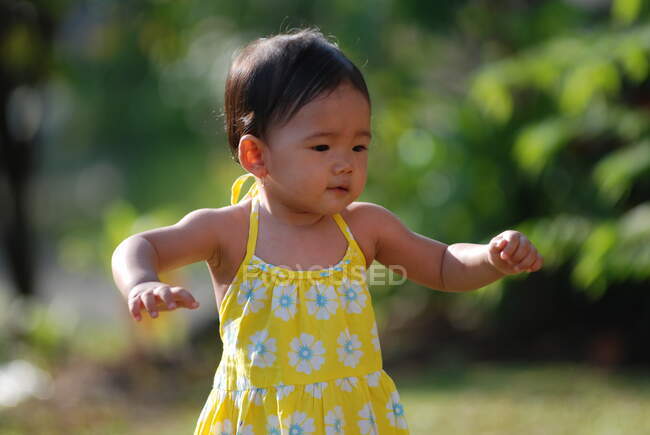 Retrato de una niña aprendiendo a caminar en un jardín, Indonesia - foto de stock