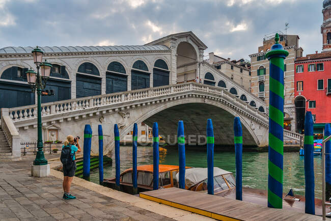 Женщина фотографирует двух мужчин, стоящих на мосту Риальто, Венеция, Венеция, Италия — стоковое фото