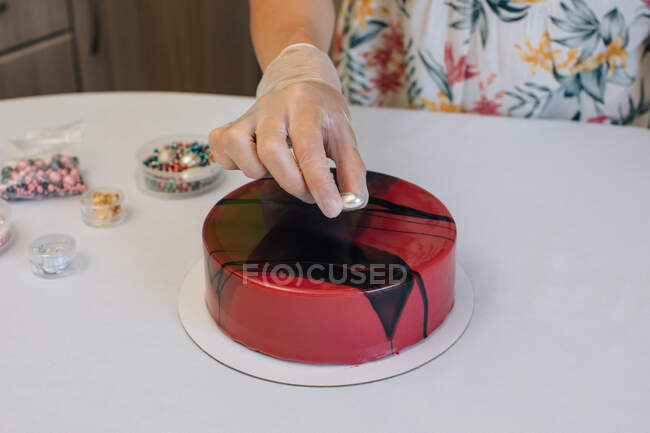 Frau dekoriert einen hausgemachten Schokoladenkuchen aus rotem Samt — Stockfoto
