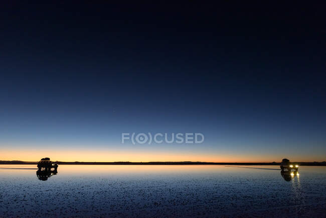 Silhouette di due auto all'alba sul piatto di sale Uyuni, Altiplano, Bolivia — Foto stock