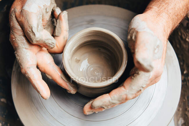 Las manos de Potter trabajando arcilla en el volante de un alfarero - foto de stock
