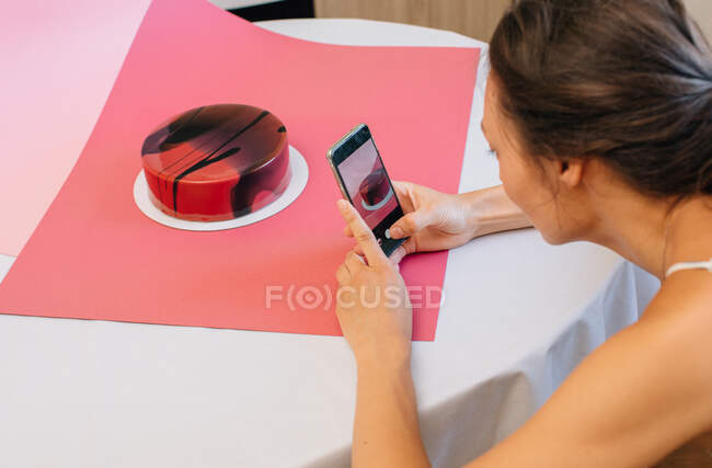 Femme photographiant un gâteau de velours rouge — Photo de stock