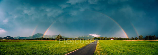 Arco-íris duplo sobre uma estrada através da paisagem rural, Salzburgo, Áustria — Fotografia de Stock
