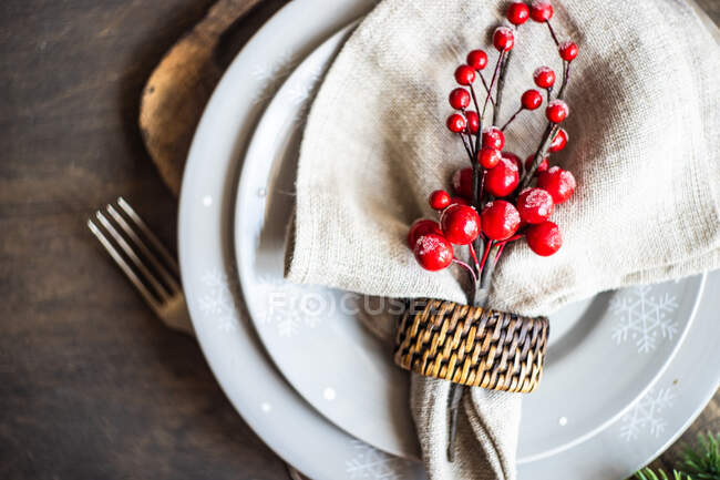 Overhead view of a Rustic Christmas place setting with berry decorations on a wooden table — Stock Photo