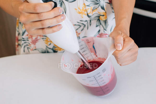 Primer plano de una mujer mezclando glaseado con una licuadora de manos - foto de stock