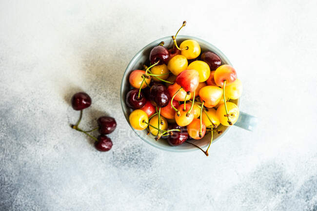 Cerezas frescas maduras en un tazón sobre un fondo gris. - foto de stock