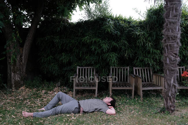 Homme allongé sur l'herbe dans un jardin, France — Photo de stock