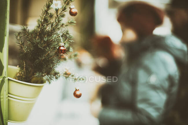 Frau steht an einer mit Weihnachtskugeln dekorierten Pflanze, Elsass, Frankreich — Stockfoto