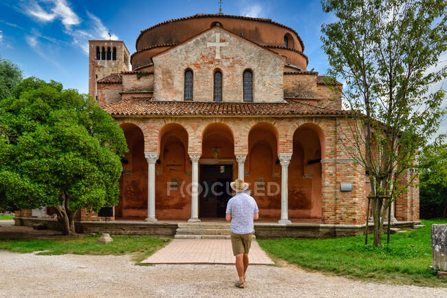 Hombre de pie frente a la Iglesia de Santa Fosca, Torcello, Venecia, Véneto, Italia - foto de stock