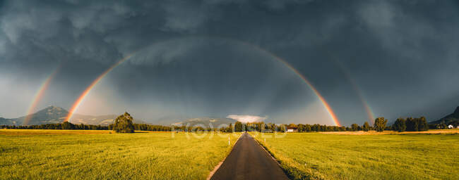 Arco-íris duplo sobre uma estrada através da paisagem rural, Salzburgo, Áustria — Fotografia de Stock