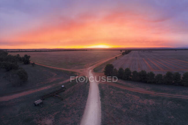 Vue aérienne d'un carrefour routier traversant des terres agricoles au lever du soleil, Australie — Photo de stock