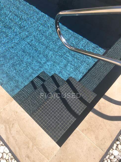 Bella piscina all'aperto in un hotel tropicale con luce solare e ombrellone — Foto stock