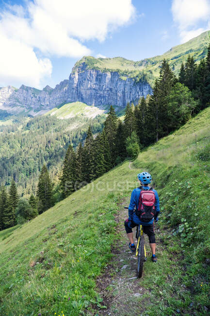 Visão traseira do homem em sua bicicleta de montanha olhando para a vista nos alpes suíços, Suíça — Fotografia de Stock