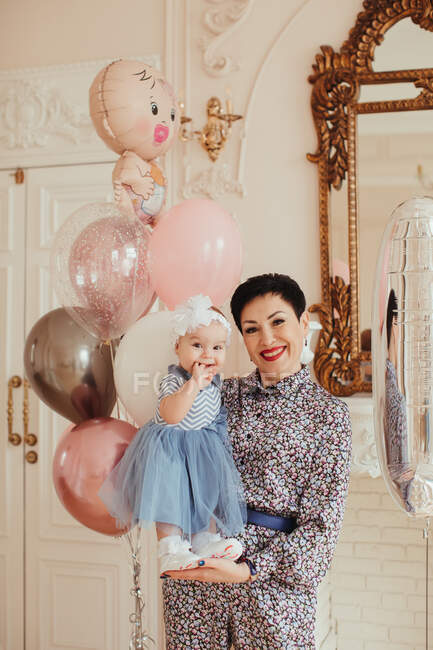 Ritratto di una donna sorridente che stringe la nipote al suo primo compleanno — Foto stock