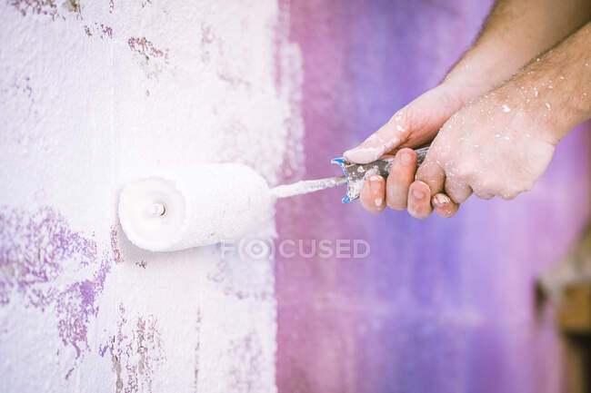 Close-up de um homem pintando uma parede com um rolo de tinta — Fotografia de Stock
