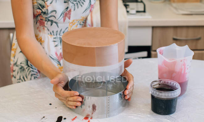 Mujer quitando un pastel de chocolate de terciopelo rojo de una lata para hornear - foto de stock